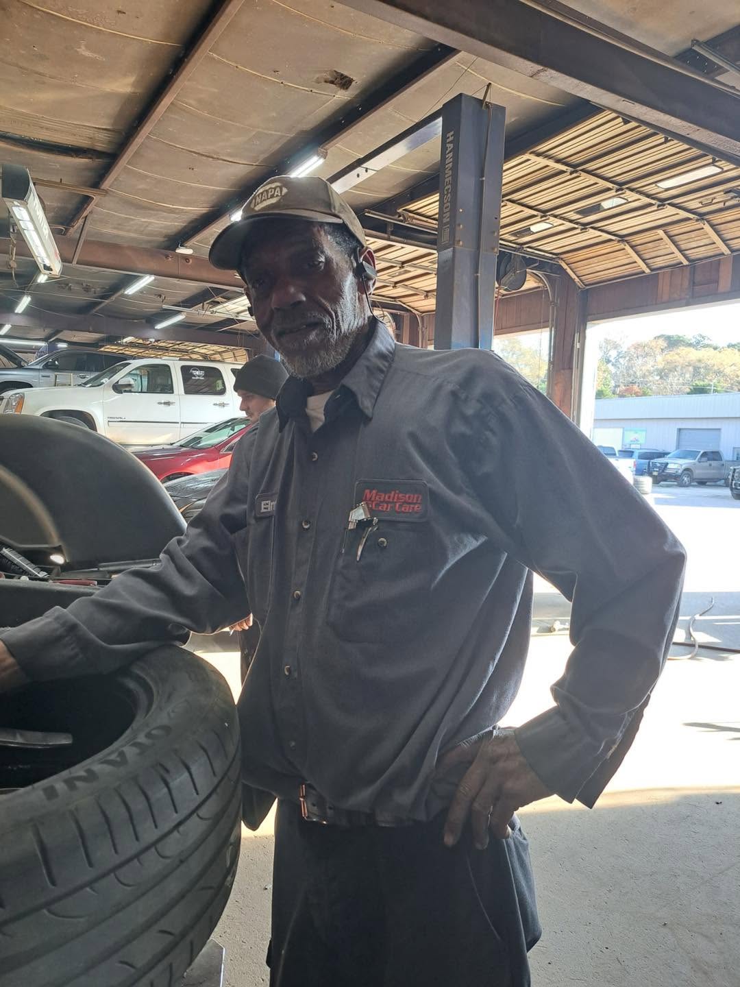 A Madison Car Care technician working with a tire